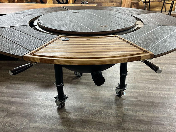 Wooden cutting board attachment on a multi-functional outdoor grill table with wheels.