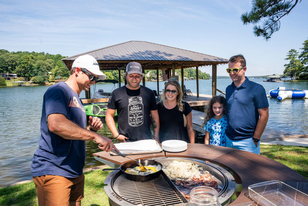 Group cooking breakfast on multi-function outdoor grill by lakeside dock