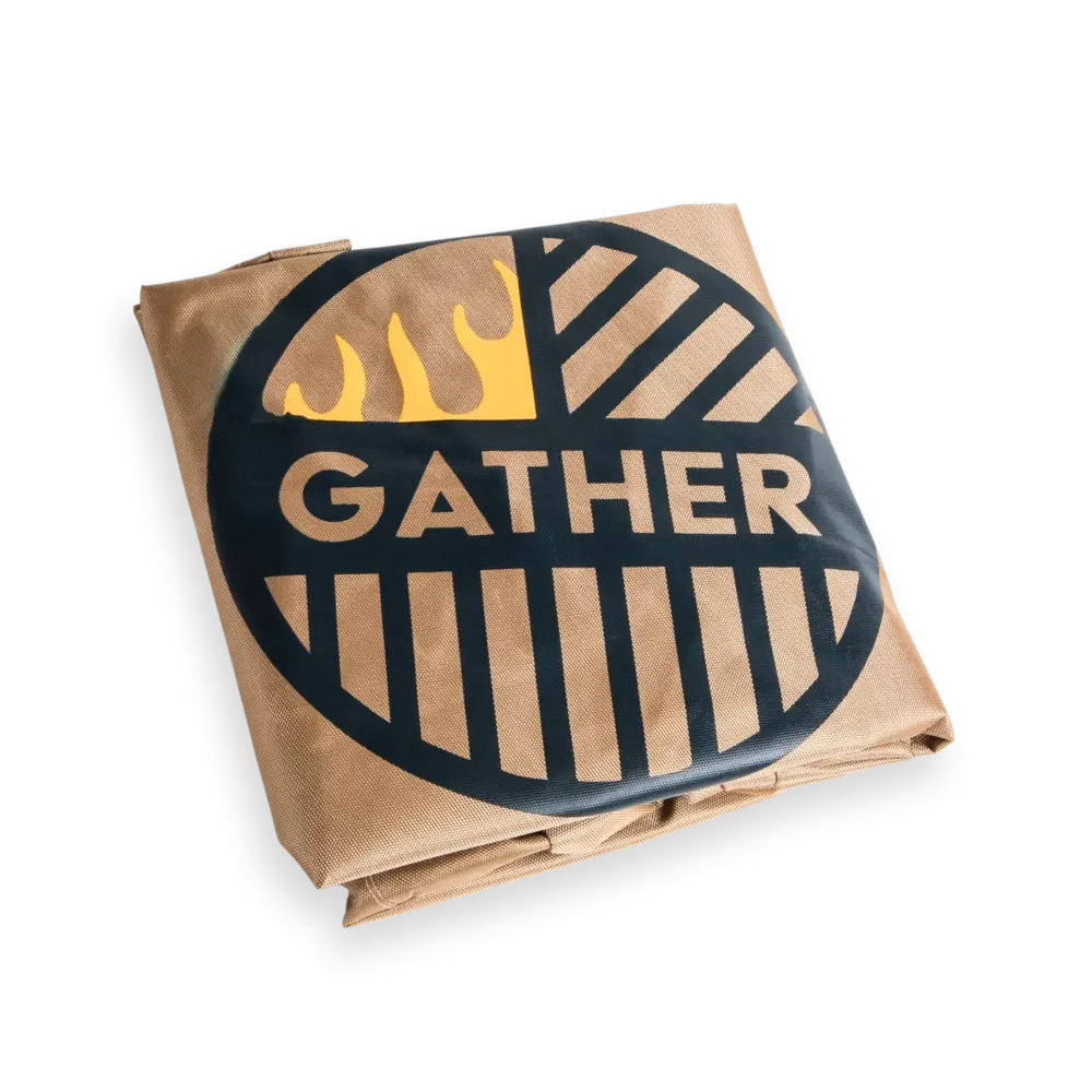 Folded grill cover with 'GATHER' logo, flame graphic, and brown fabric on black background