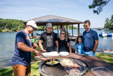 Group cooking breakfast on multi-function outdoor grill by lakeside dock