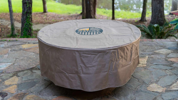 Round grill cover protecting outdoor multi-functional charcoal grill on stone patio