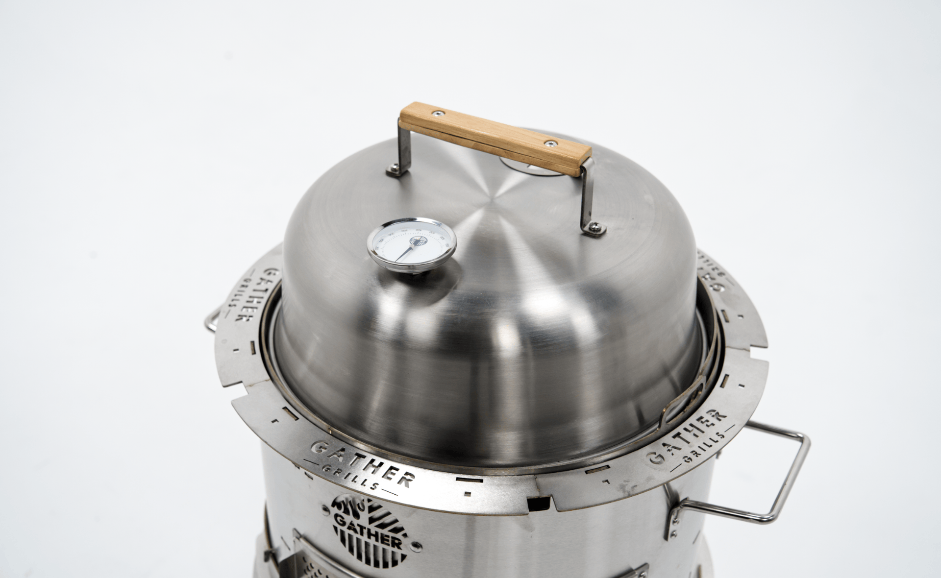 Stainless steel charcoal grill with thermometer and wood handle lid on white background
