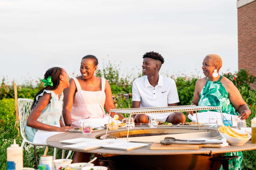 Family enjoying outdoor dining around a charcoal grill table on a sunny rooftop