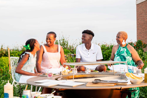 Family enjoying outdoor dining around a charcoal grill table on a sunny rooftop