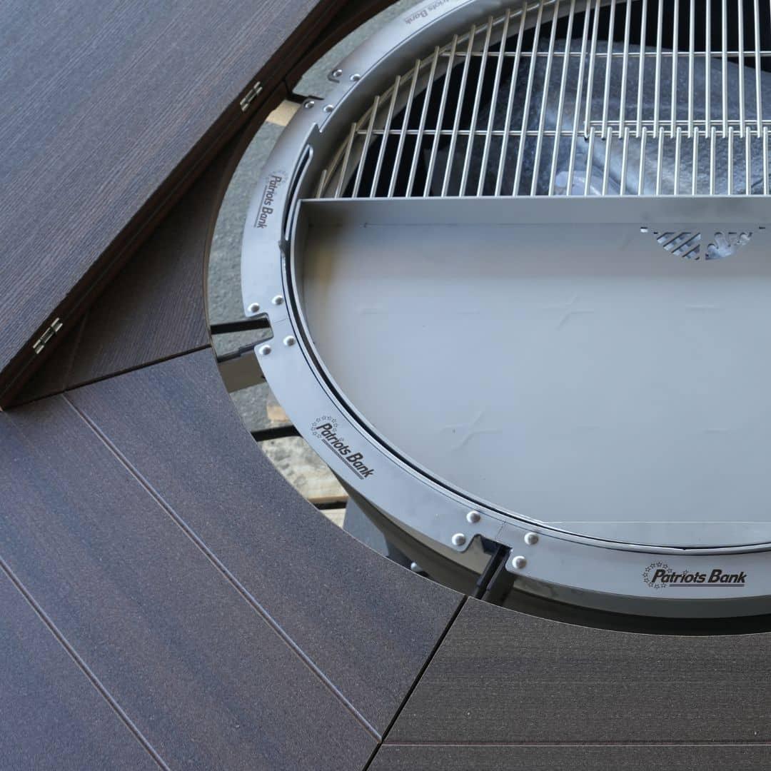 Custom stainless steel charcoal grill with wood accent and engraved logo on metal ring