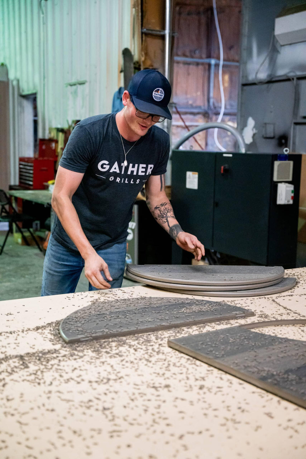 Worker assembling stainless steel charcoal grill parts in industrial workshop