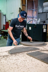 Worker assembling stainless steel charcoal grill parts in industrial workshop